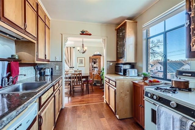 kitchen featuring white appliances, a sink, dark wood-type flooring, backsplash, and a chandelier