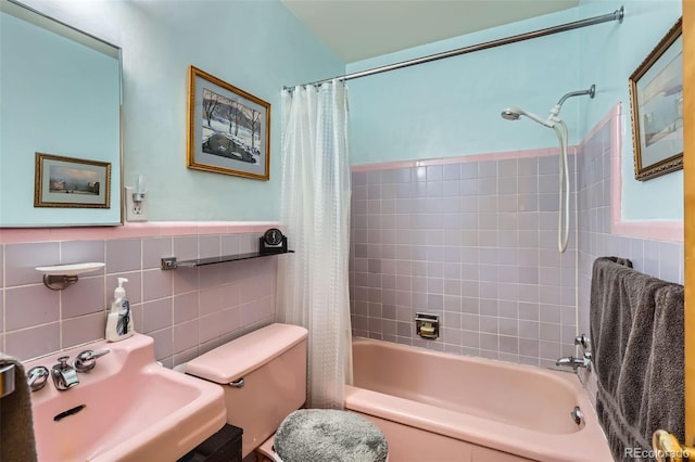 bathroom featuring a wainscoted wall, shower / bath combo with shower curtain, toilet, a sink, and tile walls