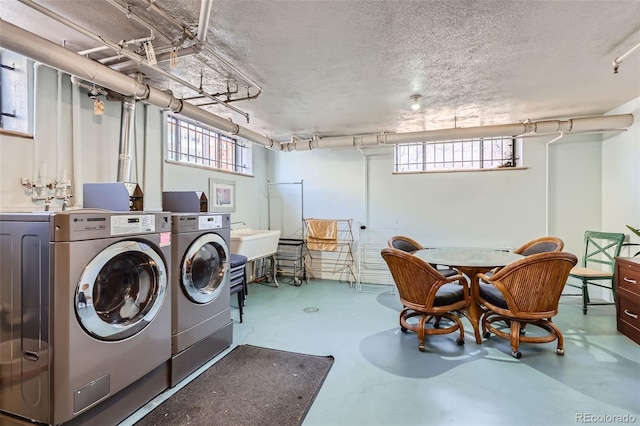 washroom featuring a textured ceiling, laundry area, and washing machine and clothes dryer