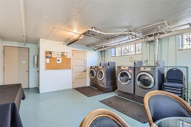 community laundry room with washer and dryer and a textured ceiling