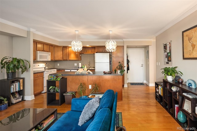 living room featuring ornamental molding, sink, a chandelier, and light hardwood / wood-style floors