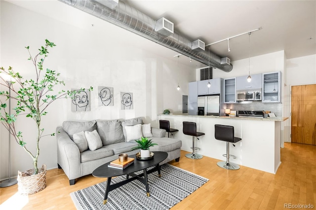 living area with light wood-style floors, track lighting, and a high ceiling