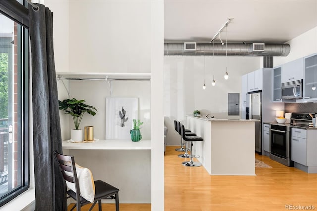 kitchen with visible vents, modern cabinets, a breakfast bar area, light wood-style flooring, and stainless steel appliances