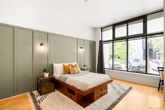 bedroom with light wood finished floors and a decorative wall