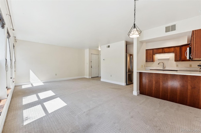 kitchen with stainless steel fridge, sink, light colored carpet, and pendant lighting