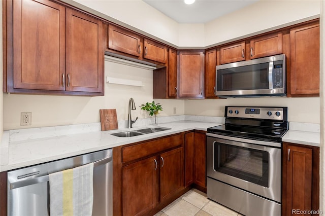 kitchen featuring sink, light stone countertops, stainless steel appliances, and light tile patterned floors