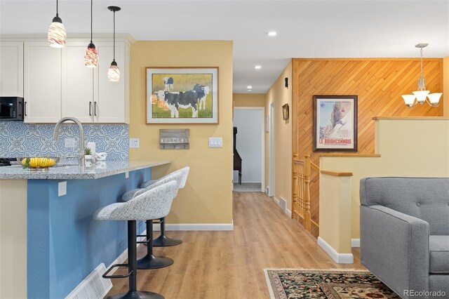 15000 W 29th Ave, Golden, CO 80401 - kitchen featuring black microwave, white cabinetry, light wood-style flooring, light stone counters, and baseboards