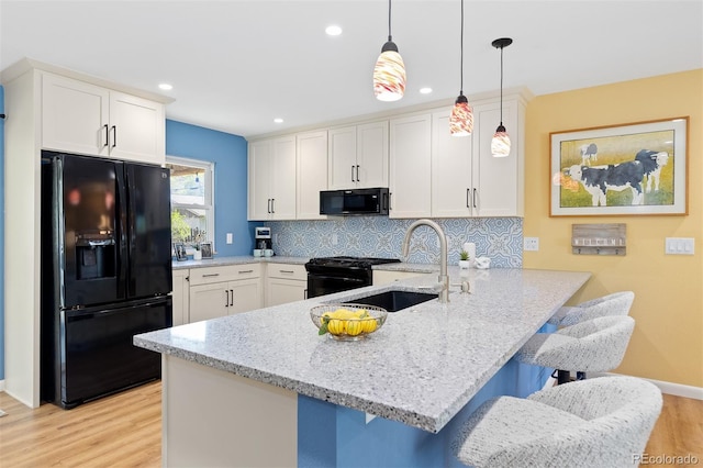 15000 W 29th Ave, Golden, CO 80401 - kitchen featuring black appliances, a peninsula, light wood-style floors, decorative backsplash, and white cabinetry