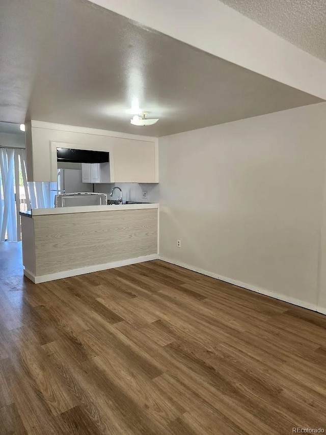 kitchen with dark hardwood / wood-style floors, kitchen peninsula, a textured ceiling, and white cabinets