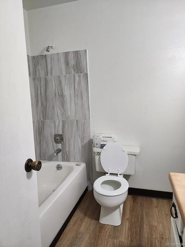 full bathroom with vanity, hardwood / wood-style flooring, tiled shower / bath combo, and toilet