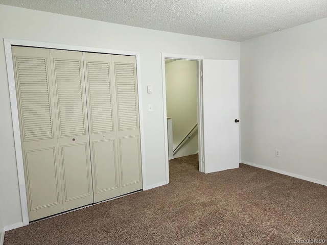 unfurnished bedroom with carpet floors, a textured ceiling, and a closet