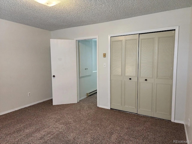 unfurnished bedroom with baseboard heating, a closet, a textured ceiling, and dark colored carpet