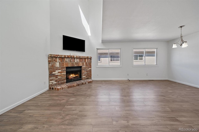 4246 S Granby St Unit B, Aurora, CO 80014 - unfurnished living room with wood finished floors, a brick fireplace, and a chandelier