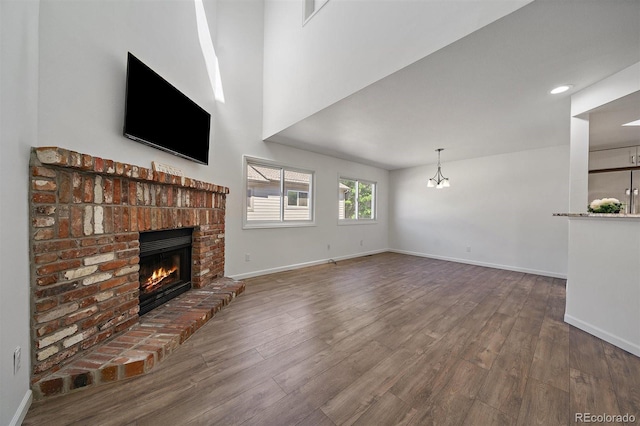 4246 S Granby St Unit B, Aurora, CO 80014 - unfurnished living room with a brick fireplace, wood finished floors, and a chandelier