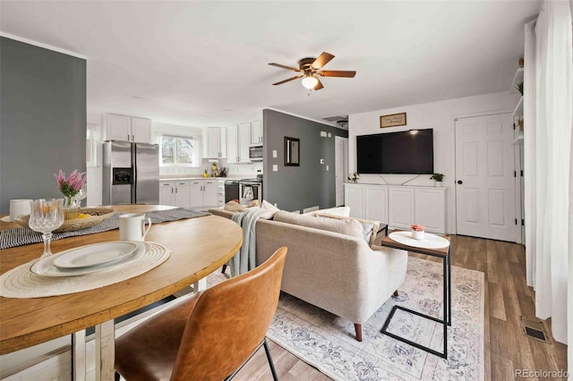 dining space featuring a ceiling fan, visible vents, and wood finished floors