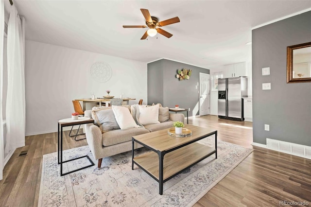 living room with ceiling fan, baseboards, visible vents, and wood finished floors