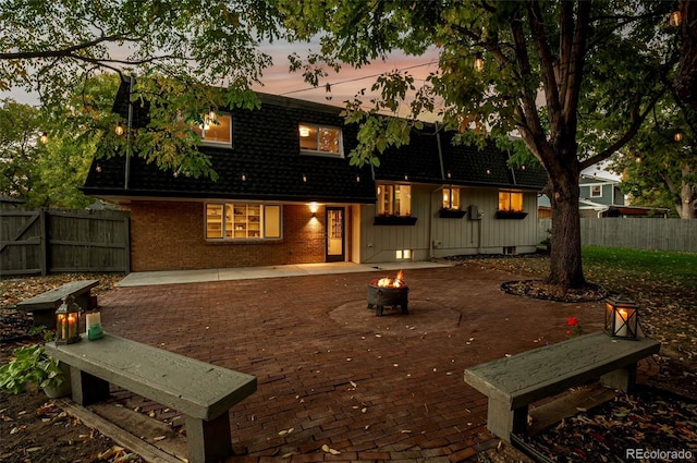 back house at dusk featuring an outdoor fire pit and a patio area