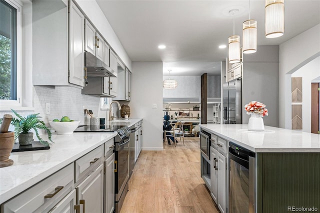 kitchen featuring a kitchen island, light hardwood / wood-style flooring, hanging light fixtures, wine cooler, and appliances with stainless steel finishes