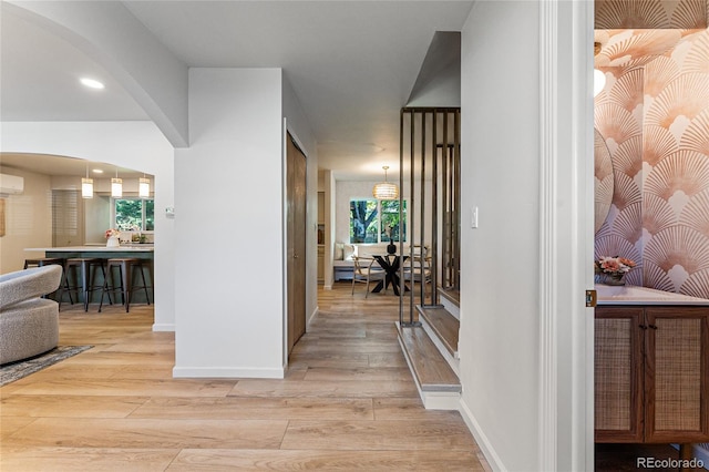 hallway with light hardwood / wood-style floors and an AC wall unit