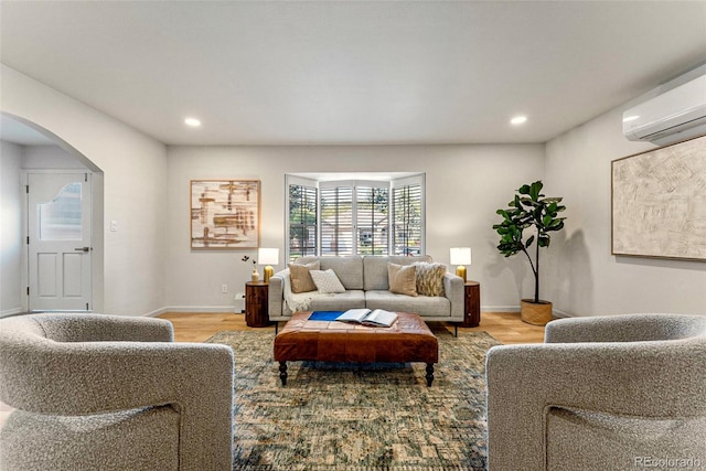 living room with an AC wall unit and light wood-type flooring