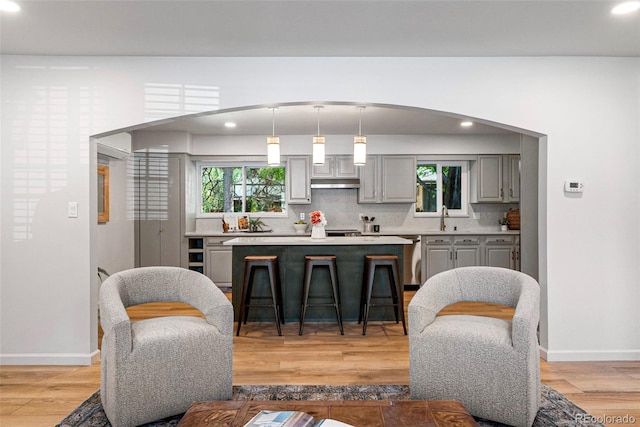 kitchen featuring tasteful backsplash, sink, gray cabinetry, light hardwood / wood-style floors, and decorative light fixtures