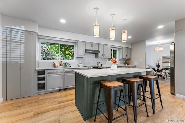 kitchen with light hardwood / wood-style floors, decorative light fixtures, and a kitchen island