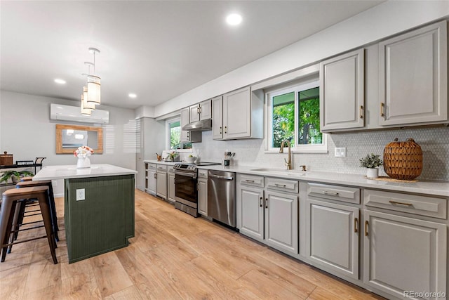 kitchen with light wood-type flooring, stainless steel appliances, a wealth of natural light, pendant lighting, and gray cabinets