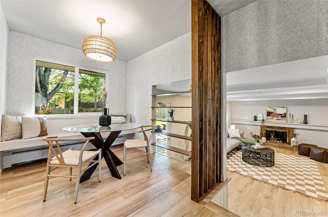 dining space with light hardwood / wood-style flooring, a brick fireplace, and breakfast area