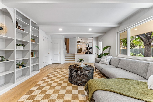 living room featuring beamed ceiling and light hardwood / wood-style flooring