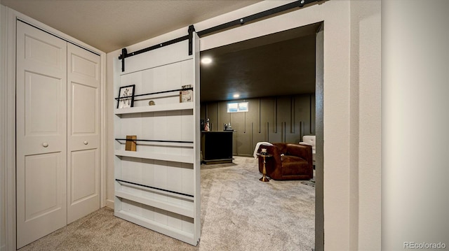 interior space featuring a closet, a textured ceiling, a barn door, and light colored carpet