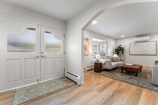 foyer featuring baseboard heating, an AC wall unit, and light wood-type flooring