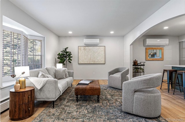 living room with baseboard heating, a wall mounted AC, and wood-type flooring