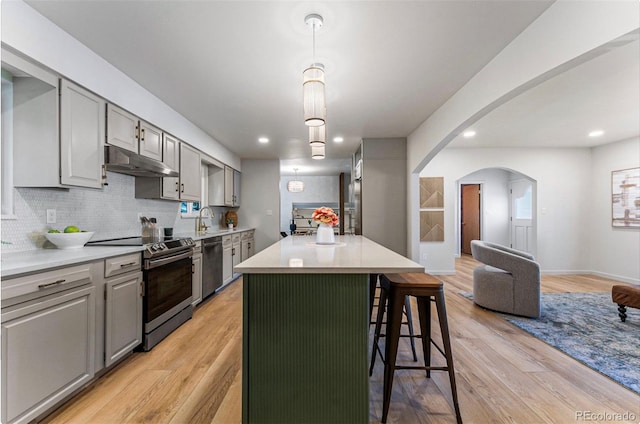 kitchen with gray cabinetry, stainless steel appliances, a center island, and light wood-type flooring