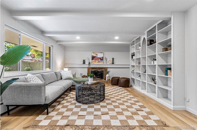 living room featuring beam ceiling, light wood-type flooring, and a fireplace