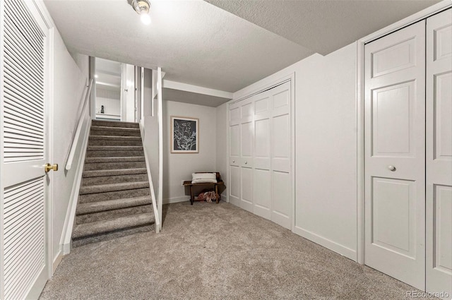 staircase with carpet and a textured ceiling