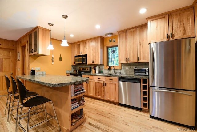 446 Blue River Rd, Breckenridge, CO 80424 - kitchen featuring stainless steel appliances, a kitchen bar, decorative backsplash, light wood finished floors, and a peninsula