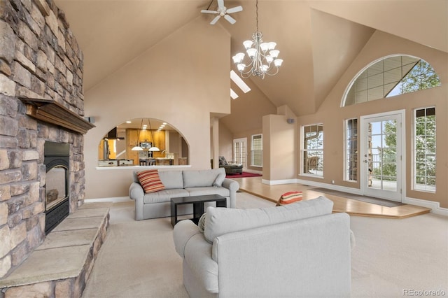 living room featuring arched walkways, a notable chandelier, a stone fireplace, high vaulted ceiling, and baseboards