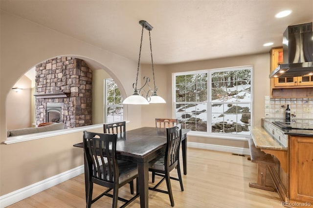 6530 Ridgeview Dr, Morrison, CO 80465 - dining area with light wood-type flooring, baseboards, arched walkways, a fireplace, and recessed lighting