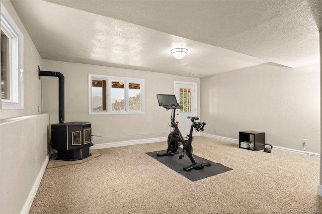 6530 Ridgeview Dr, Morrison, CO 80465 - workout area featuring carpet floors, a textured ceiling, a wood stove, and baseboards