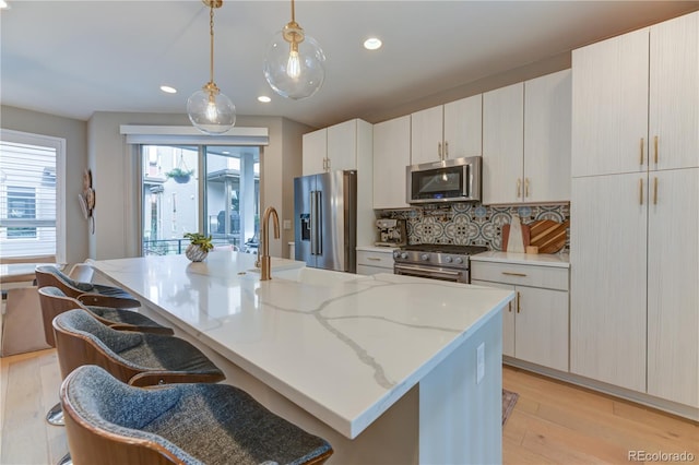 kitchen featuring a kitchen bar, a kitchen island with sink, high end appliances, and pendant lighting