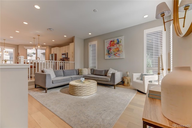 living room featuring light wood-type flooring, a wealth of natural light, and an inviting chandelier