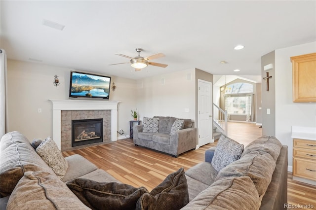 living room featuring a tile fireplace, light wood-type flooring, and ceiling fan