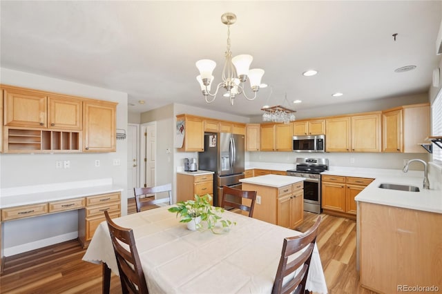 kitchen with hardwood / wood-style floors, appliances with stainless steel finishes, a center island, an inviting chandelier, and sink