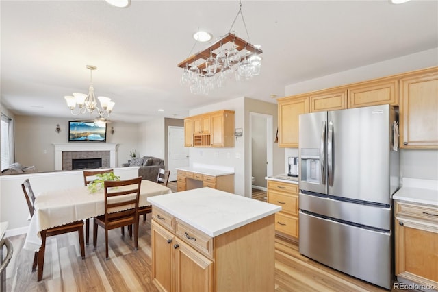 kitchen with a center island, light hardwood / wood-style floors, a fireplace, hanging light fixtures, and stainless steel fridge