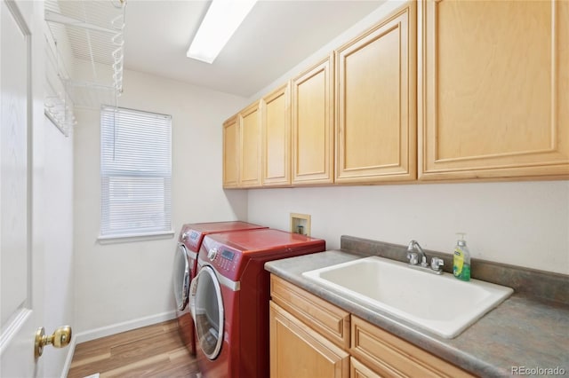 washroom featuring sink, cabinets, light wood-type flooring, and washing machine and clothes dryer