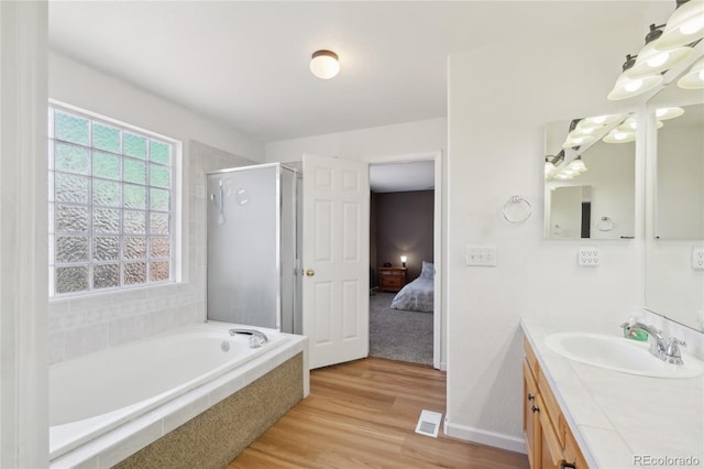 bathroom with hardwood / wood-style floors, separate shower and tub, and vanity