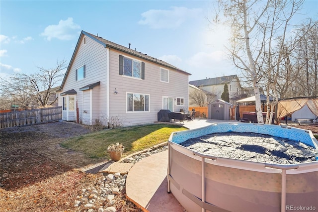 rear view of property featuring a fenced in pool, a storage shed, and a yard