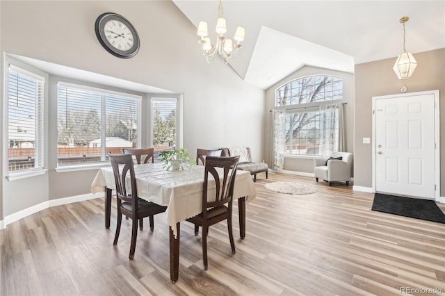 dining space with light wood-type flooring, vaulted ceiling, and a notable chandelier