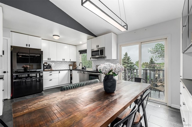 19661 E Girard Ave, Aurora, CO 80013 - kitchen featuring stainless steel appliances, vaulted ceiling, backsplash, dark countertops, and white cabinetry