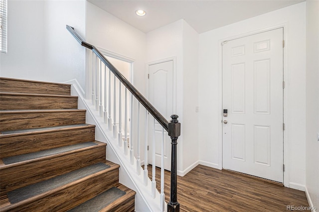 entrance foyer with dark wood-style floors, stairs, and baseboards